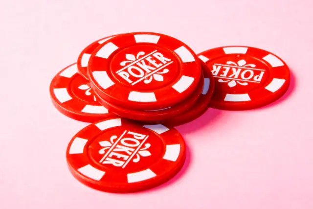 Red poker chips scattered on a pink surface