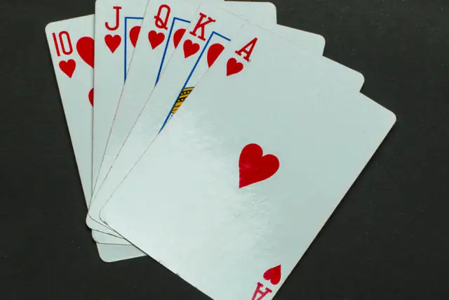 A royal flush in hearts fanned out on a black background